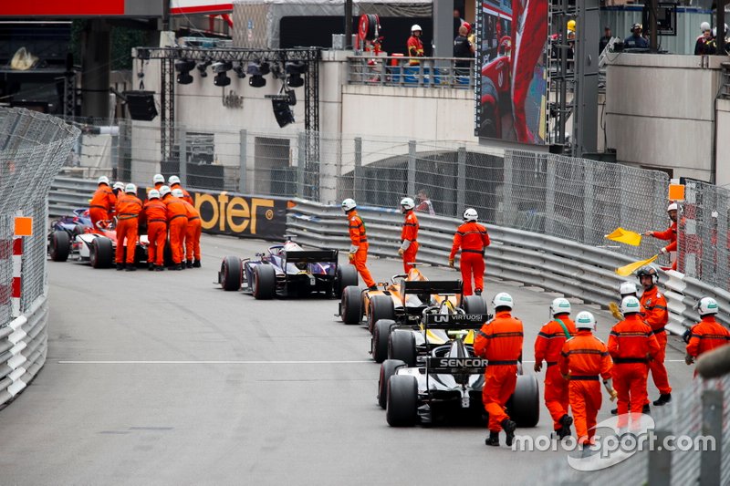 Les commissaires poussent les voitures pendant le drapeau rouge