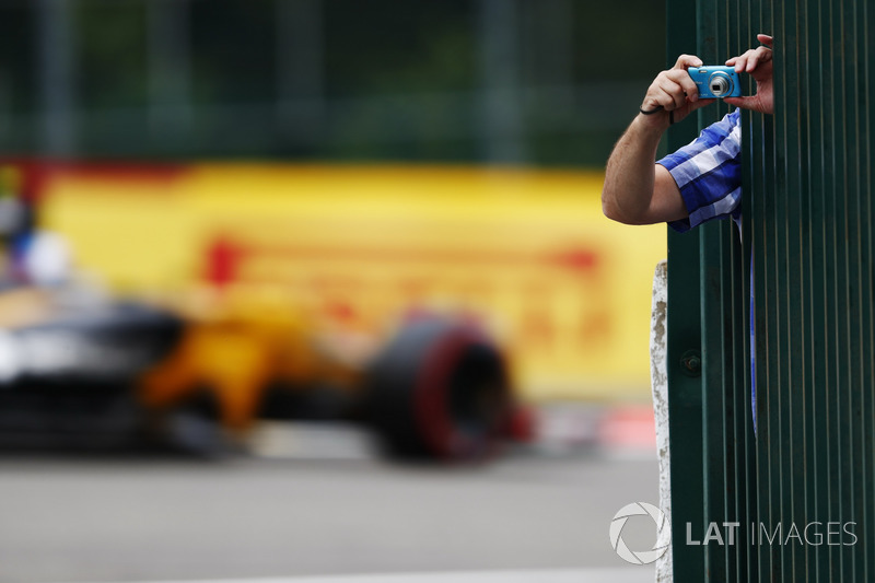 A fan leans out to take some photos as Jolyon Palmer, Renault Sport F1 Team RS17, passes through the background