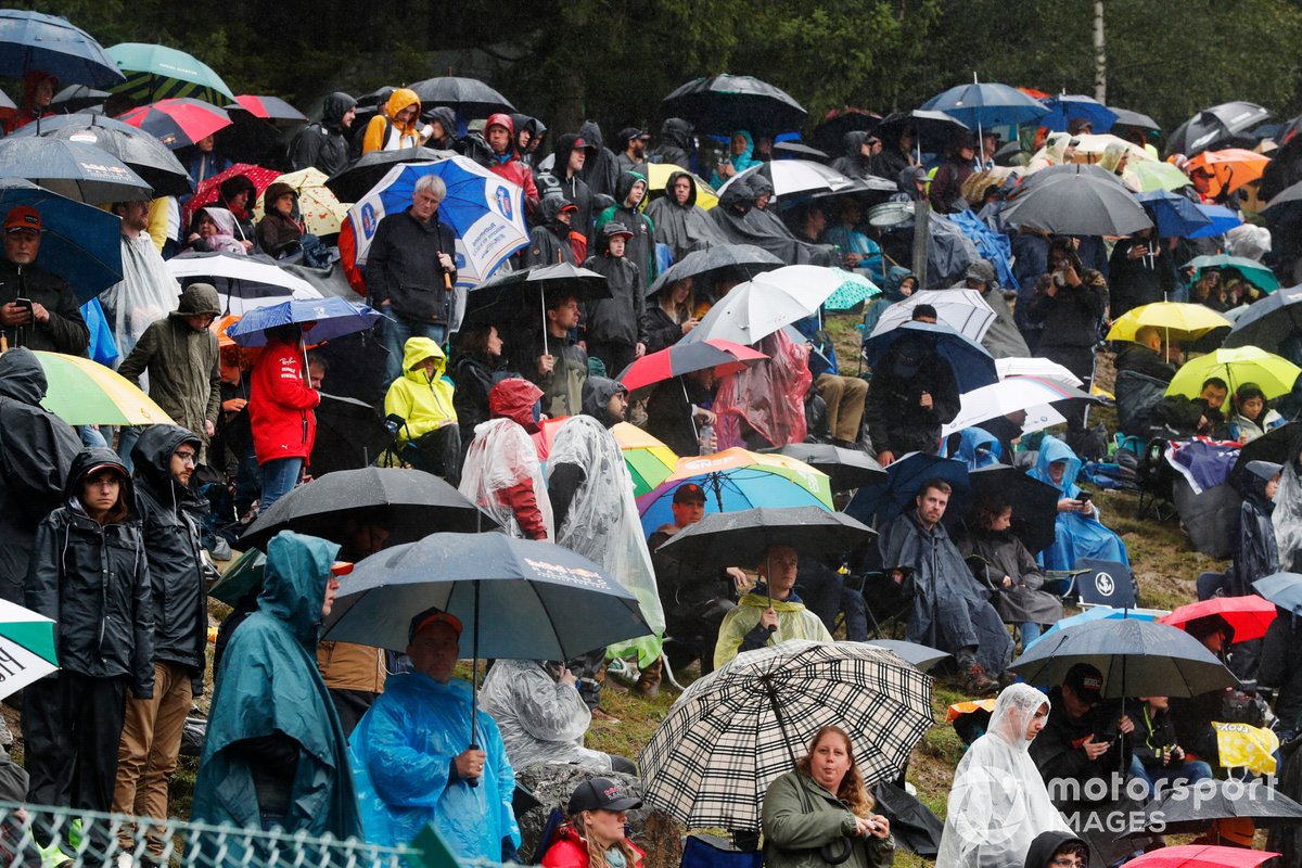 Fans menggunakan payung dan jas hujan selama menunggu periode red flag F1 GP Belgia 2021.