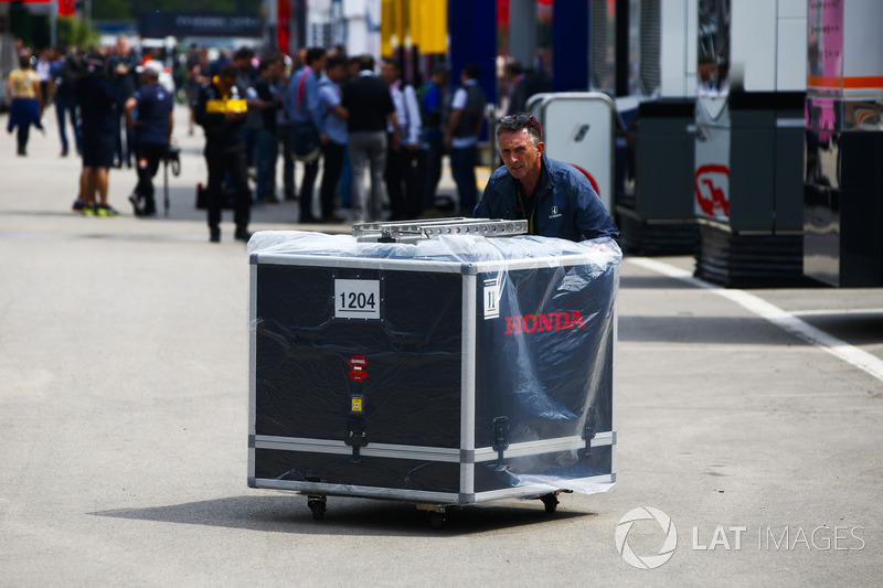 Un miembro del equipo de Honda empuja una caja de motor en el paddock