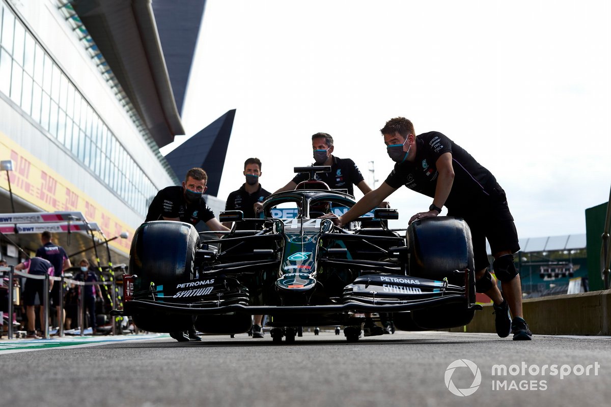 Mechanics push the Lewis Hamilton Mercedes F1 W11 in the pit lane