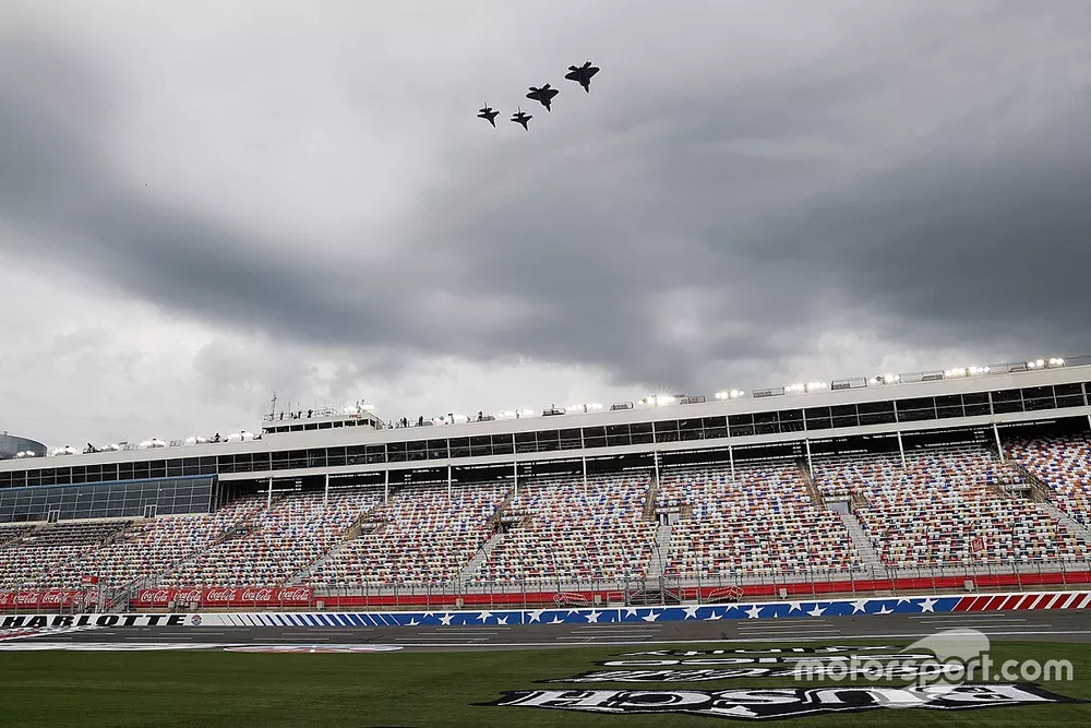 Military aircraft perform a flyover empty stands before the race