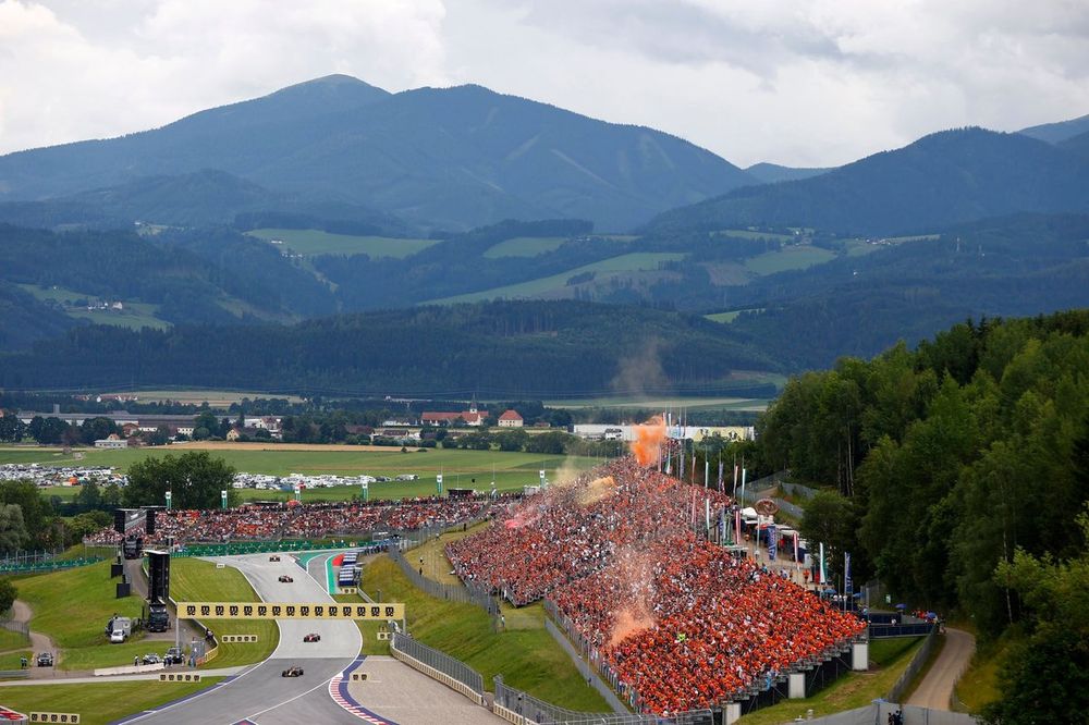 Max Verstappen, Red Bull Racing RB19, Charles Leclerc, Ferrari SF-23, Carlos Sainz, Ferrari SF-23, on the formation lap as orange smoke erupts from the grandstand