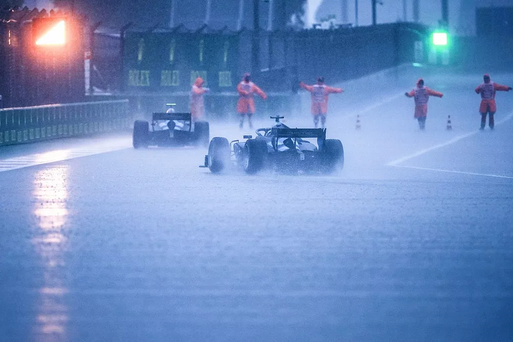 Rain lashes down in the pit lane as the red light is displayed at the exit