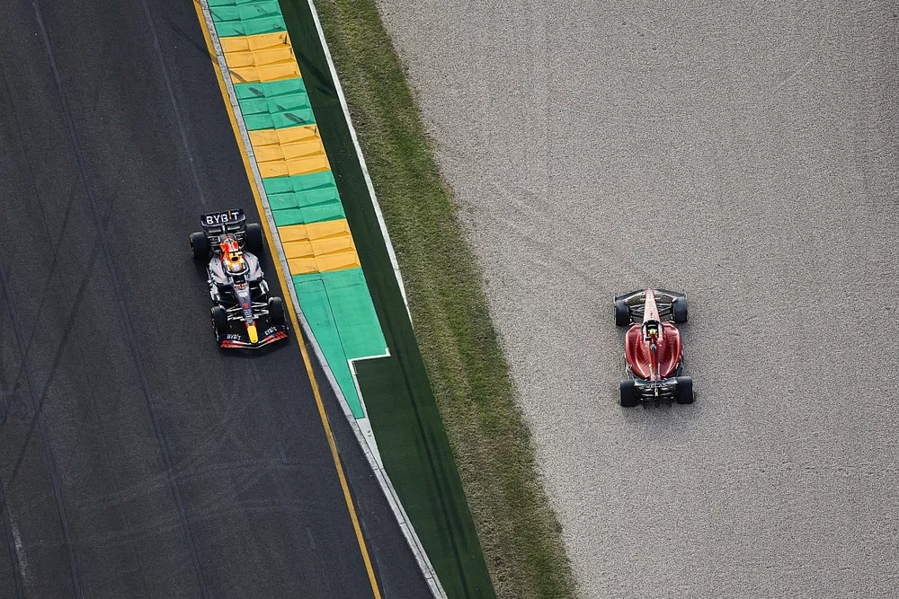 Max Verstappen, Red Bull Racing RB18, passes the beached car of Carlos Sainz Jr., Ferrari F1-75