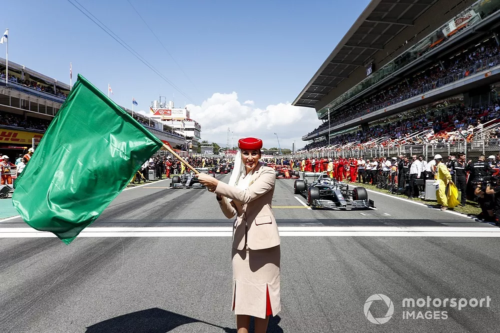 La azafata de los Emiratos ondea una bandera verde en la parrilla antes de la carrera