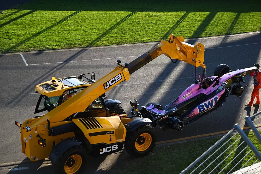 Los comisarios retiran el coche dañado de Esteban Ocon, Alpine A523, del circuito con una JCB