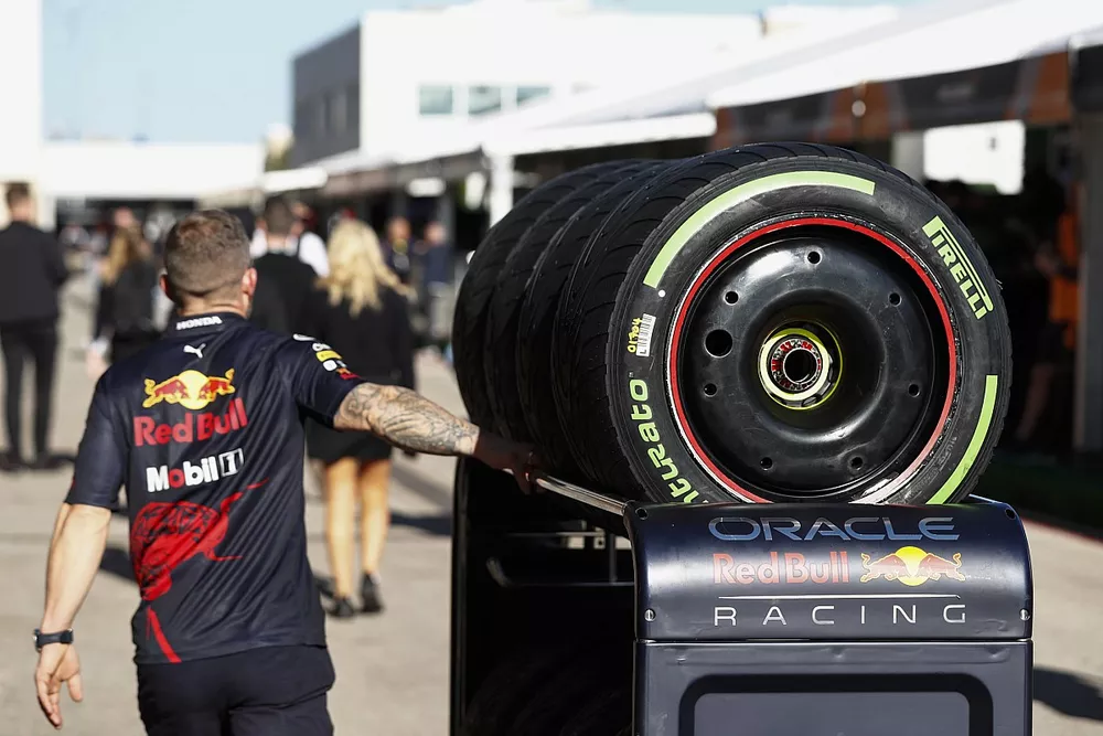 A Red Bull Racing mechanic wheels Pirelli tyres through the paddock