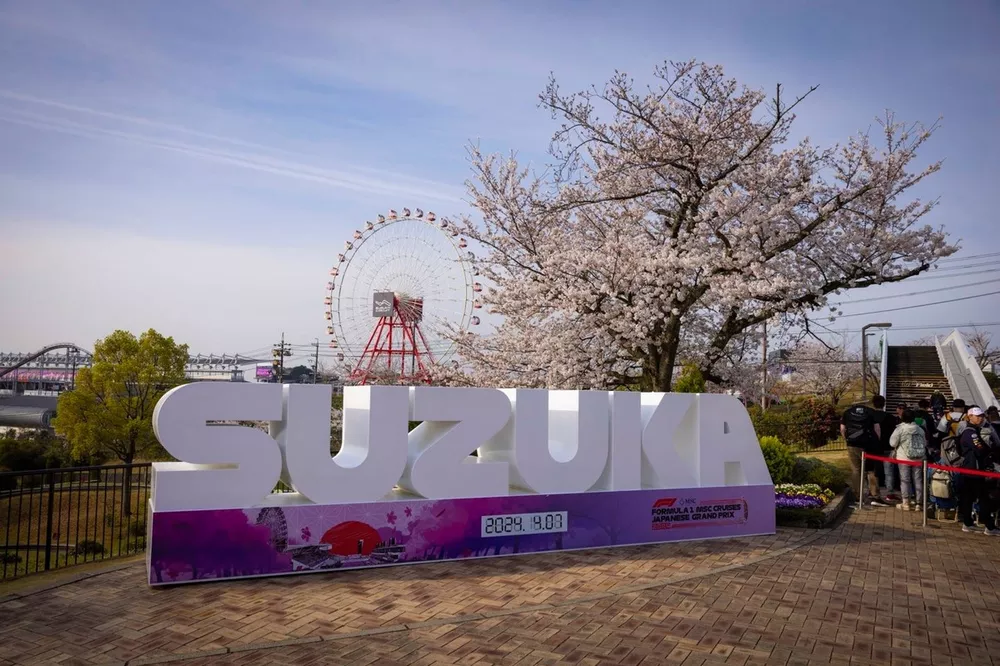 Fans enter the circuit next to a sign for Suzuka. The Ferris wheel is visible behind