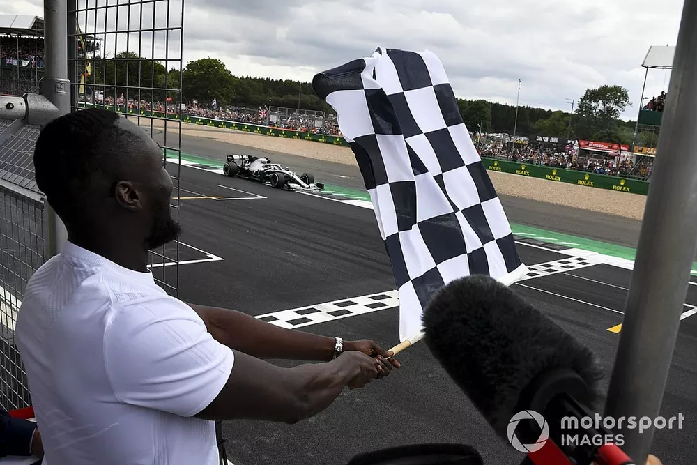 Stormzy, Rapero ondea la bandera de llegada mientras Lewis Hamilton, Mercedes AMG F1 W10 cruza la línea