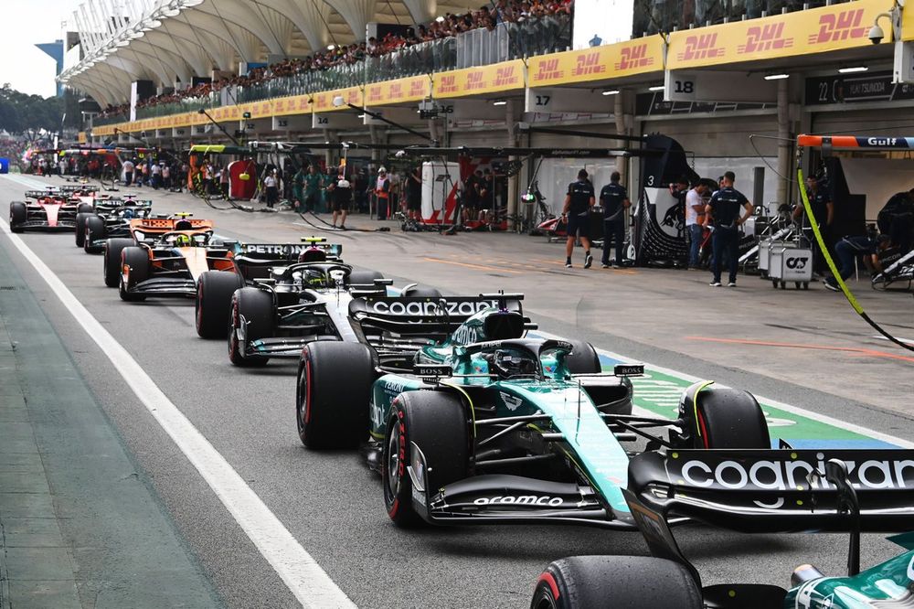 Lance Stroll, Aston Martin AMR23, leads Sir Lewis Hamilton, Mercedes F1 W14, and Lando Norris, McLaren MCL60, in the pit lane