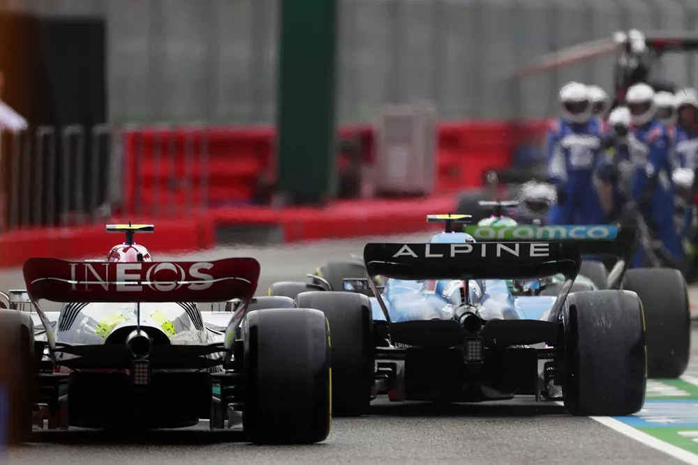 Esteban Ocon, Alpine A522, en la trayectoria de Lewis Hamilton, Mercedes W13, en el pit lane