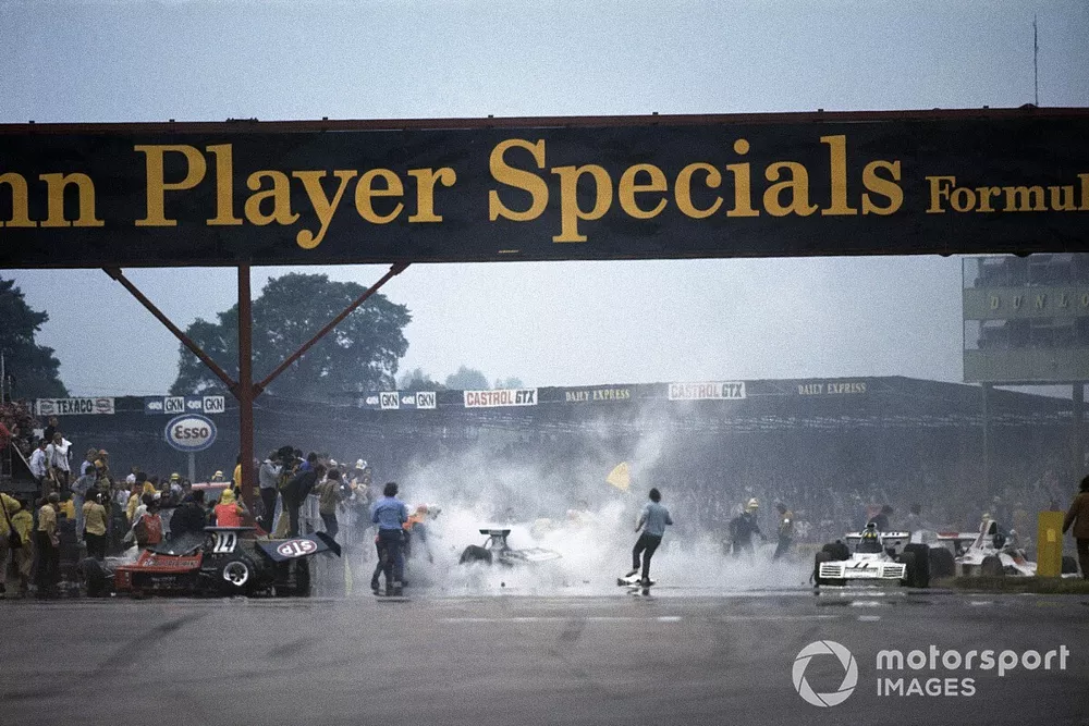 Trabajos de limpieza despu&eacute;s del accidente en la primera vuelta. El Ford Ford March 731 de Roger Williamson a la izquierda, mientras que el Ford Brabham BT42 de Wilson Fittipaldi da&ntilde;ado y Graham Hill detiene su Ford Shadow SN1
