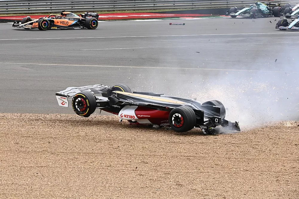 Zhou Guanyu, Alfa Romeo C42, slides across the gravel during a crash at the start