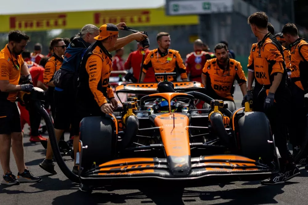 Mechanics push Oscar Piastri, McLaren MCL38, to his grid slot