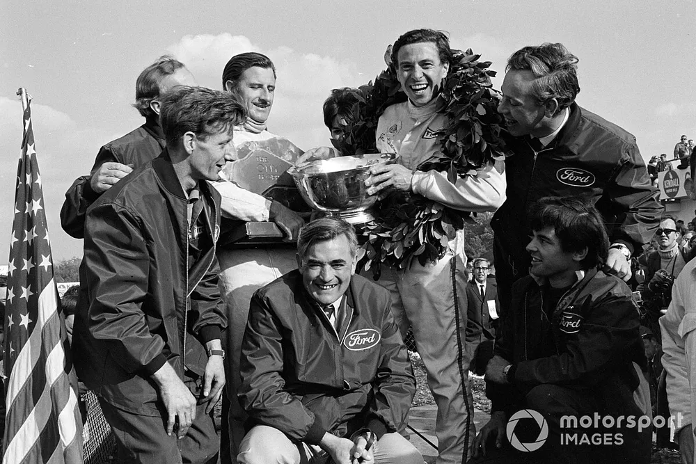 Ford Cosworth designers and engineers celebrate the Lotus 1-2 with Colin Chapman, Graham Hill and Jim Clark