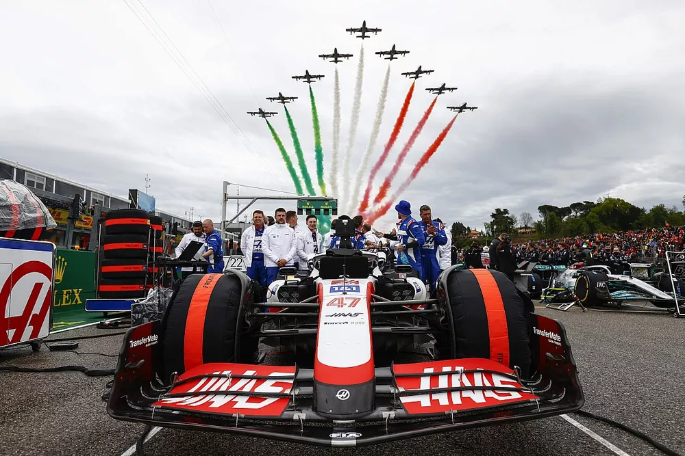 Mec&aacute;nicos en la parrilla con el coche de Mick Schumacher, Haas VF-22, mientras el equipo de exhibici&oacute;n acrob&aacute;tica de la Fuerza A&eacute;rea Italiana