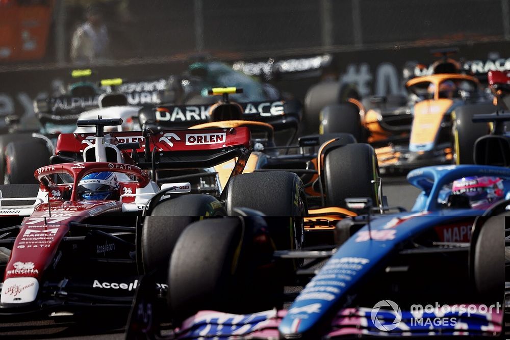 Fernando Alonso, Alpine A522, leads Valtteri Bottas, Alfa Romeo C42, Lando Norris, McLaren MCL36, and the remainder of the field