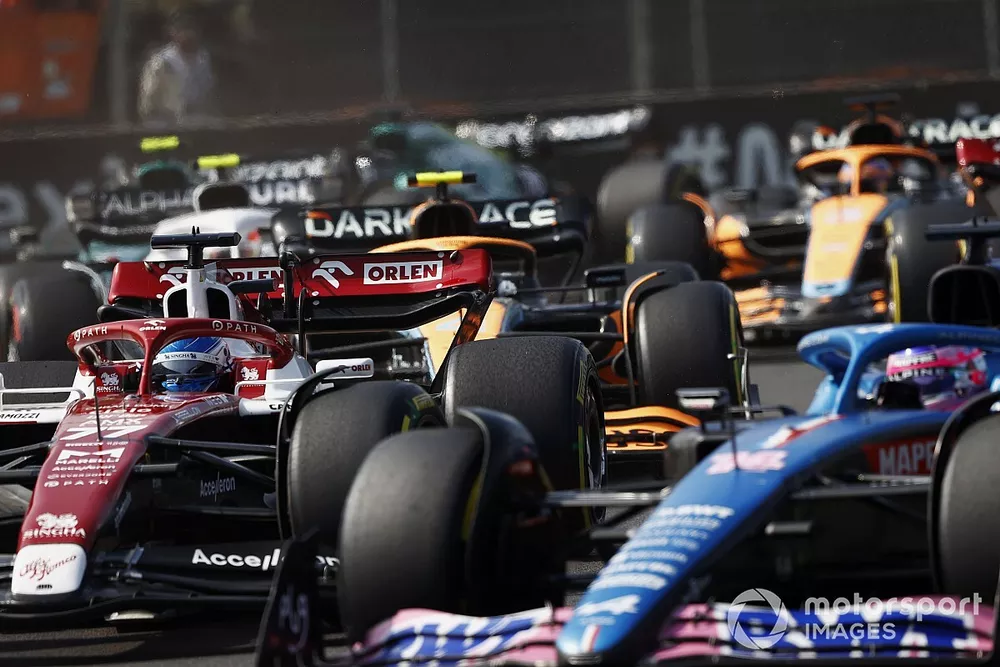Fernando Alonso, Alpine A522, leads Valtteri Bottas, Alfa Romeo C42, Lando Norris, McLaren MCL36, and the remainder of the field