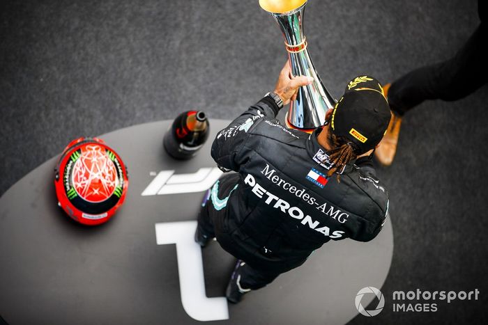 Lewis Hamilton, Mercedes-AMG F1, 1ª posición, en el podio con su trofeo y el casco de Michael Schumacher