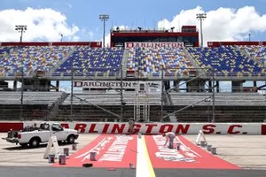 Track workers paint logos on the front stretch