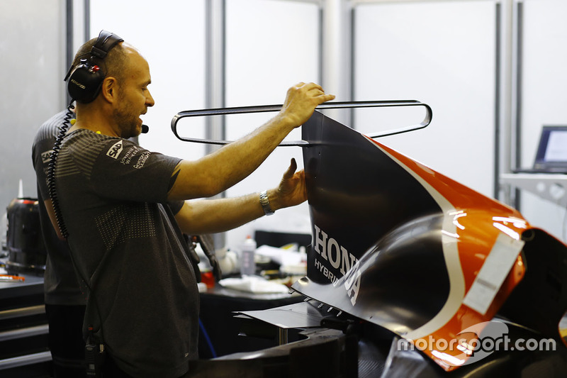 A McLaren team member works on an engine cover