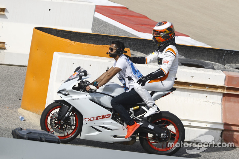 Stoffel Vandoorne, McLaren, gets a lift back on a motorbike