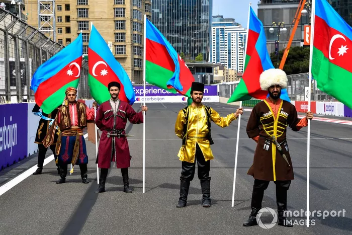 Artistas con trajes tradicionales con banderas de Azerbaiyán en la parrilla