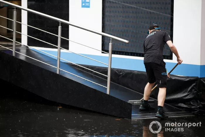 Un miembro de Williams Racing trata de achicar agua de la entrada del motorhome