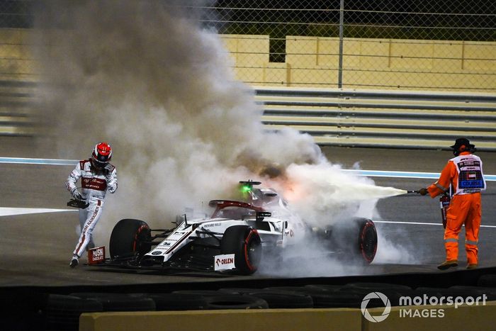 Kimi Raikkonen, Alfa Romeo Racing C39, ayuda a un oficial de pista a apagar el incendio de su monoplaza