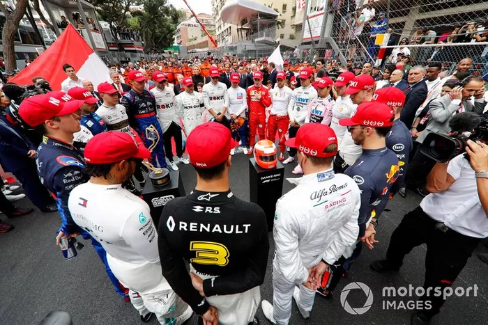 Pilotos en un minuto de silencio con gorra roja en homenaje a Niki Lauda