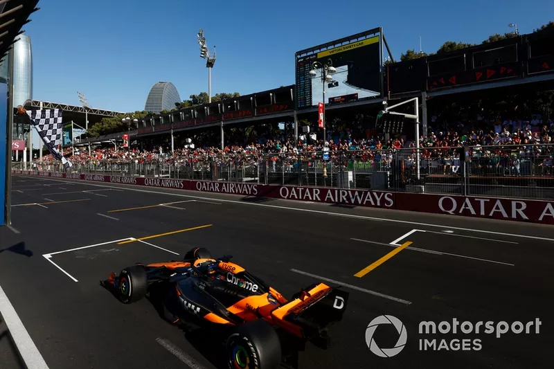 Oscar Piastri, McLaren MCL38, 1ère position, prend le drapeau à damier