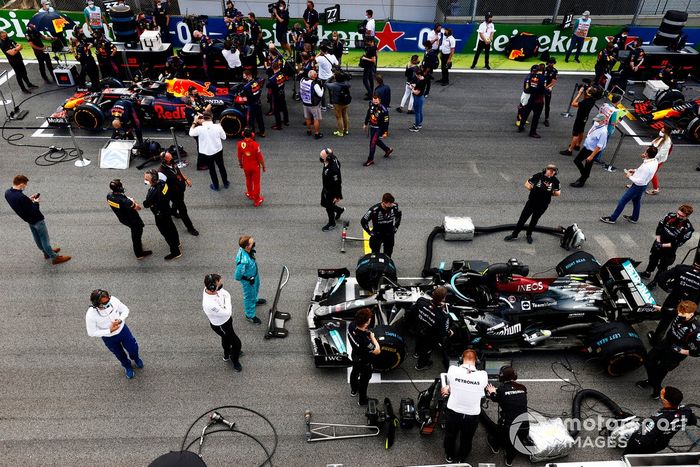 Mecánicos en la parrilla con los coches de Max Verstappen, Red Bull Racing RB16B, y Valtteri Bottas, Mercedes W12
