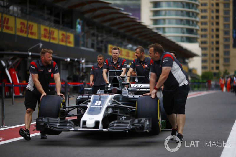 Los miembros del equipo Haas F1 Team empujan el coche de Romain Grosjean Haas F1 Team VF-17 por el pit lane