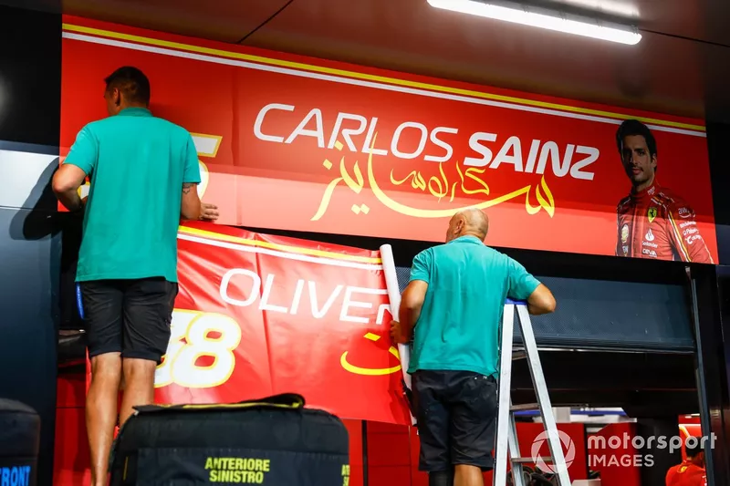 Le personnel du circuit remplace la bannière du garage de Carlos Sainz, Scuderia Ferrari, par celle d'Oliver Bearman, Scuderia Ferrari.