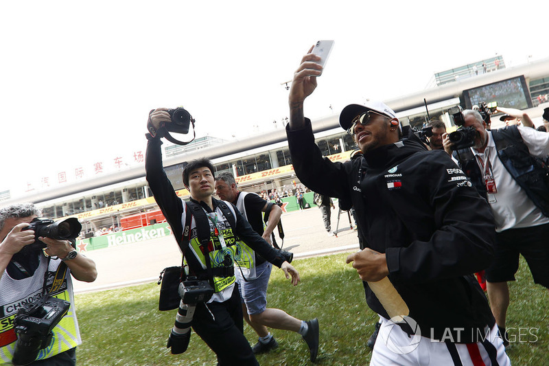 Lewis Hamilton, Mercedes AMG F1, is mobbed by photographers, as he takes a picture of fans with his smart phone