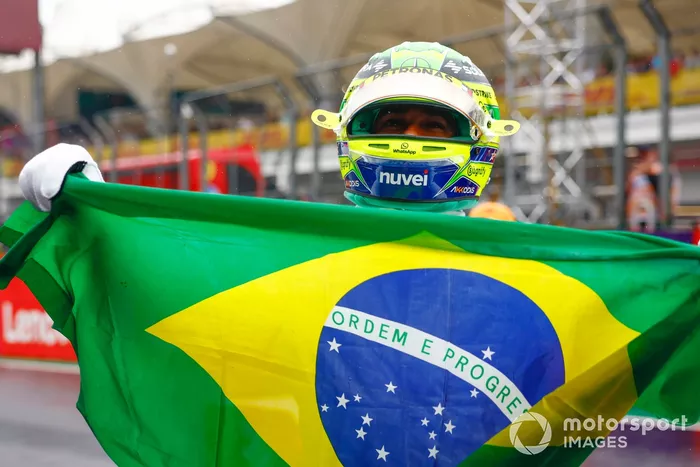 Lewis Hamilton sostiene una bandera brasileña tras pilotar el McLaren MP4/5B