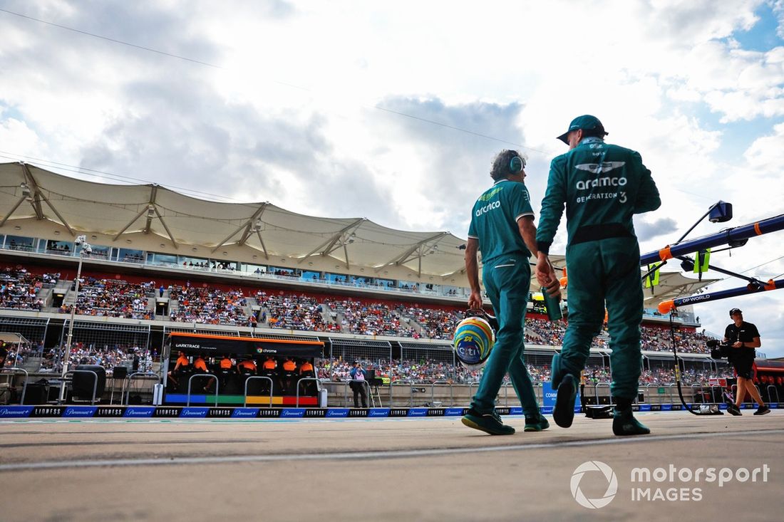 Fernando Alonso, Aston Martin F1 Team, camina por el pit lane, mientras los ingenieros de McLaren trabajan en el muro de boxes.