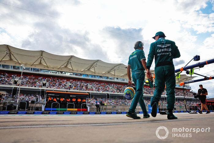 Fernando Alonso, Aston Martin F1 Team, camina por el pit lane, mientras los ingenieros de McLaren trabajan en el muro de boxes.