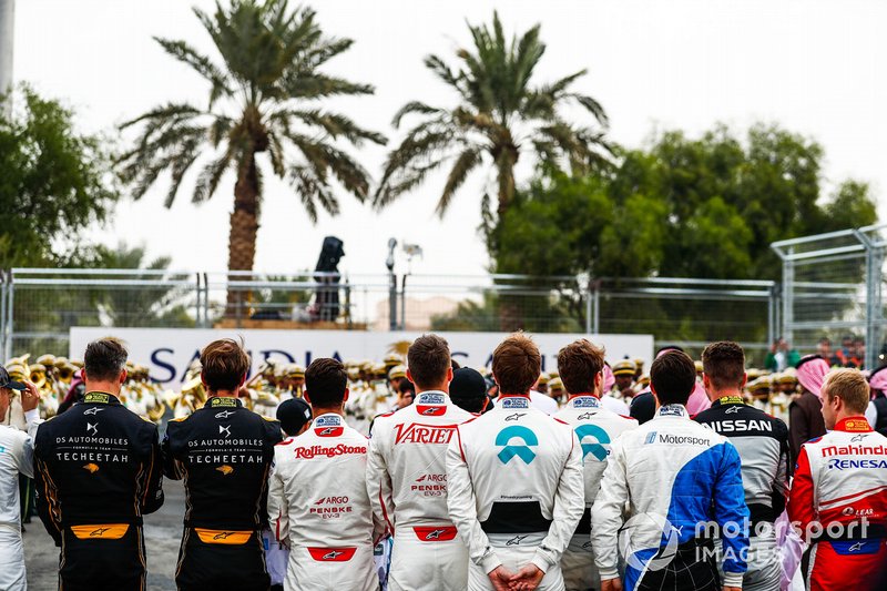 The drivers line up on the grid for the national anthem