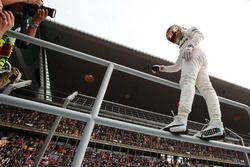 Lewis Hamilton, Mercedes AMG, climbs a fence to celebrate pole position