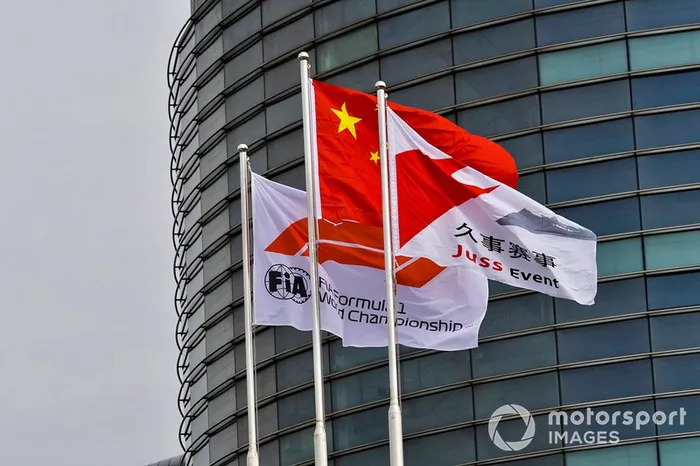 Una bandera china junto a una bandera de Fórmula 1 de la FIA y una bandera de evento de Juss.