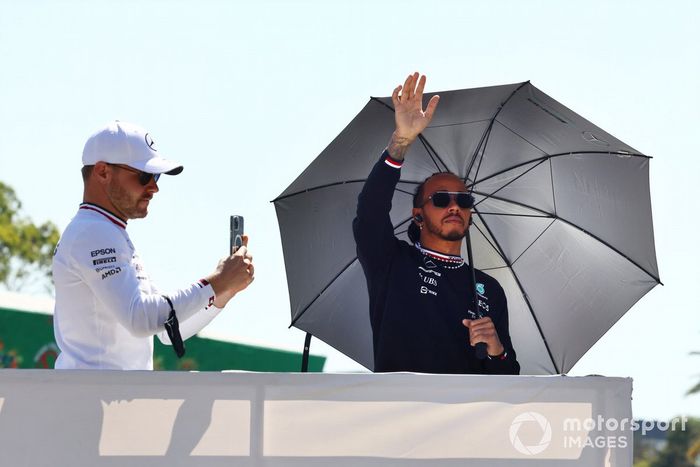 Valtteri Bottas, de Mercedes, se hace una foto mientras Lewis Hamilton, de Mercedes, saluda a los aficionados en el desfile de pilotos