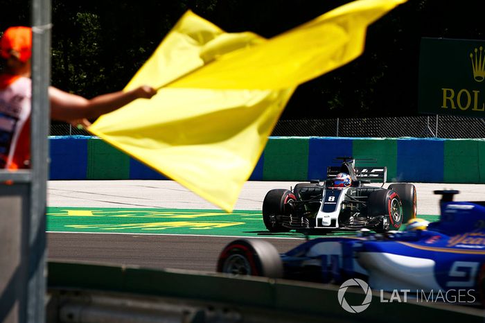 Oficiales ondean bandera amarilla con Romain Grosjean, Haas F1 Team VF-17. Marcus Ericsson, Sauber C36 pasa por la zona del incidente