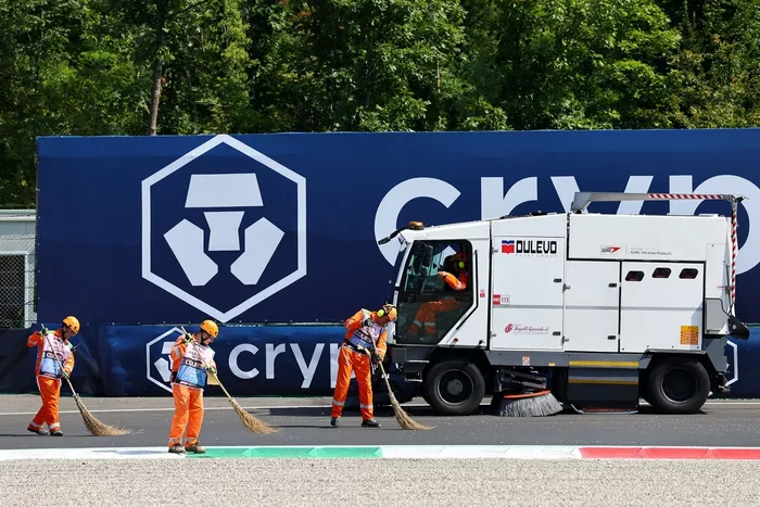Los comisarios barren la grava del circuito durante los entrenamientos.