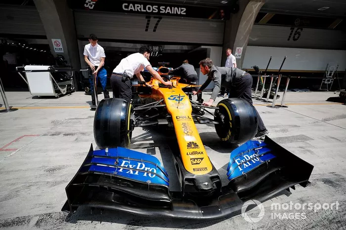 Los mecánicos de McLaren empujan el coche de Carlos Sainz Jr, McLaren MCL34, al garaje.