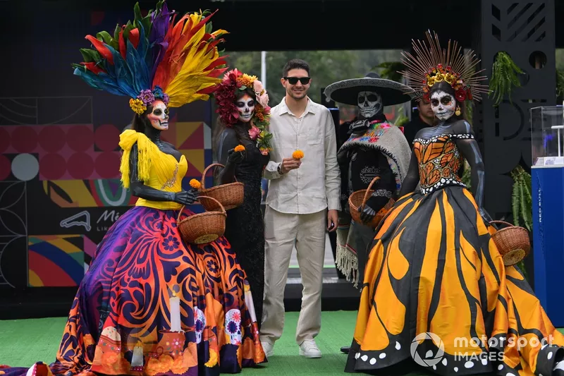 Esteban Ocon, Alpine F1 Team, holding a Mexican marigold, poses with women wearing Calaveras make up