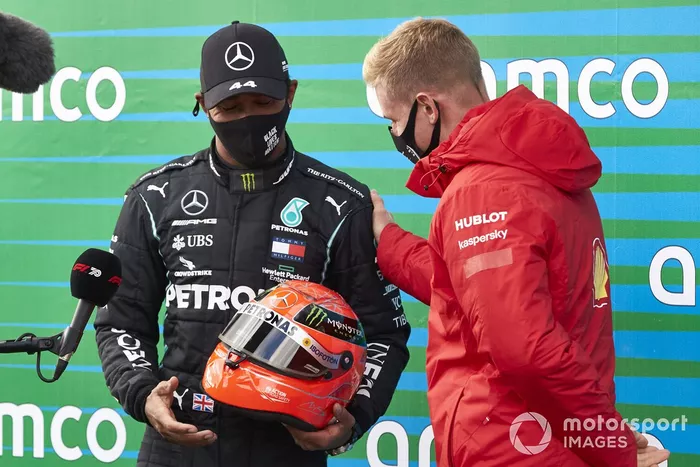 Mick Schumacher entrega a Lewis Hamilton, Mercedes-AMG F1, el casco de su padre después de que el piloto de Mercedes igualara el récord de Michael Schumacher de 91 victorias en carreras