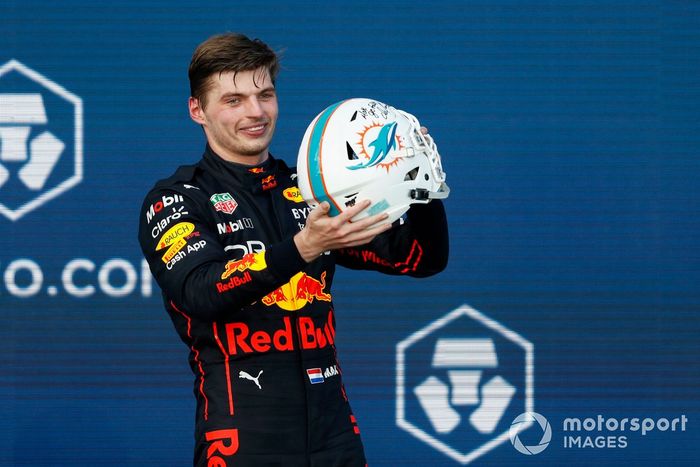 Max Verstappen, Red Bull Racing, 1ª posición, recibe un casco de fútbol de los Miami Dolphins en el podio