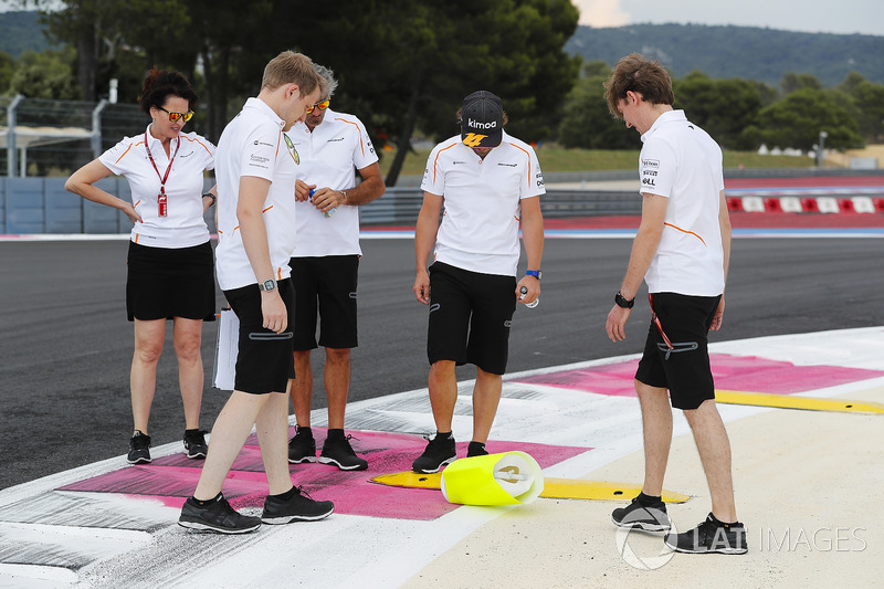 Fernando Alonso, McLaren, inspects a kerb with colleagues